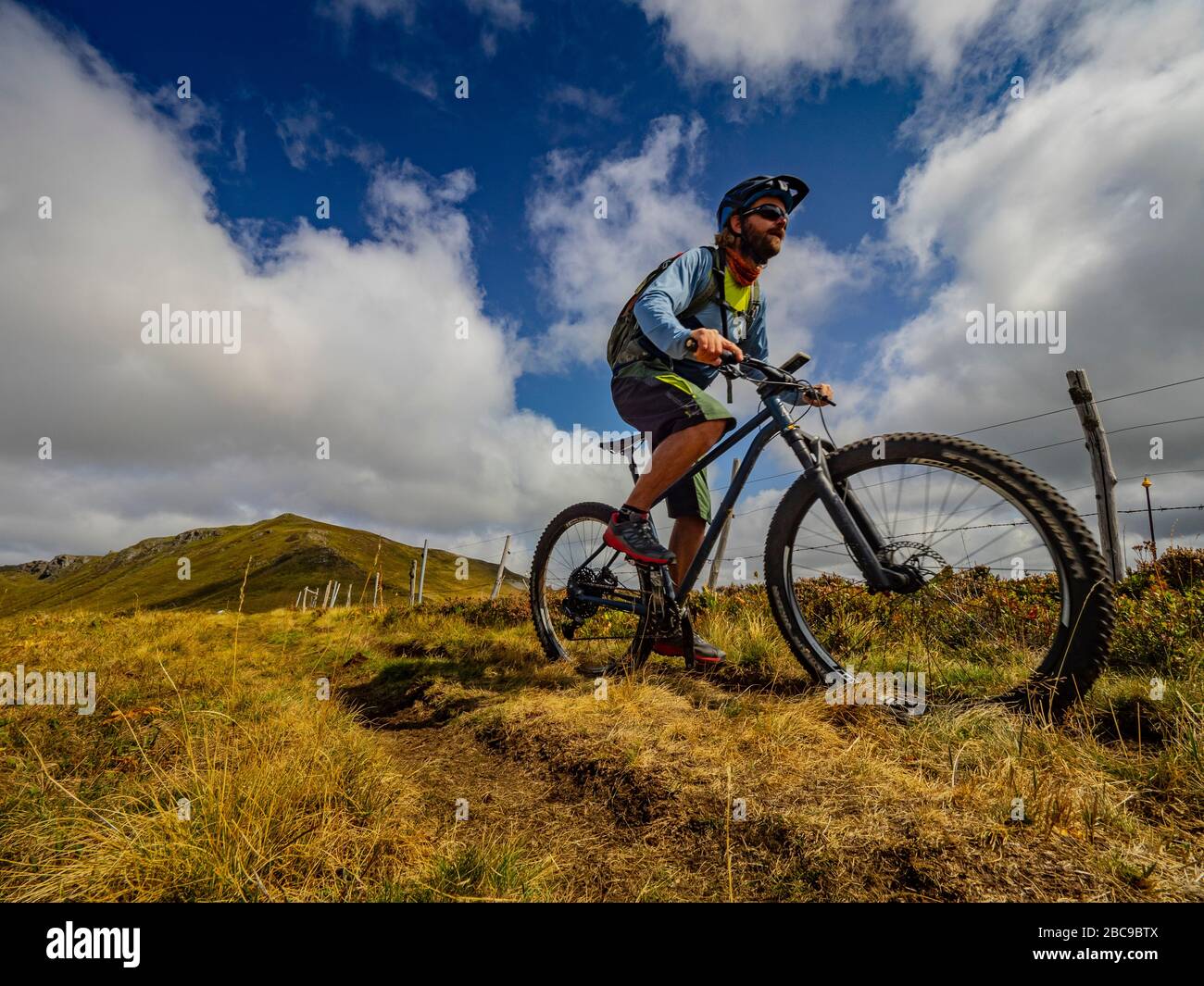 Mountain bikers su sentiero singolo GR 400. Stretto sentiero di montagna attraverso alti pascoli a le Pas Rouge. Monts du Cantal, Massif Central, Cantal Francia Foto Stock