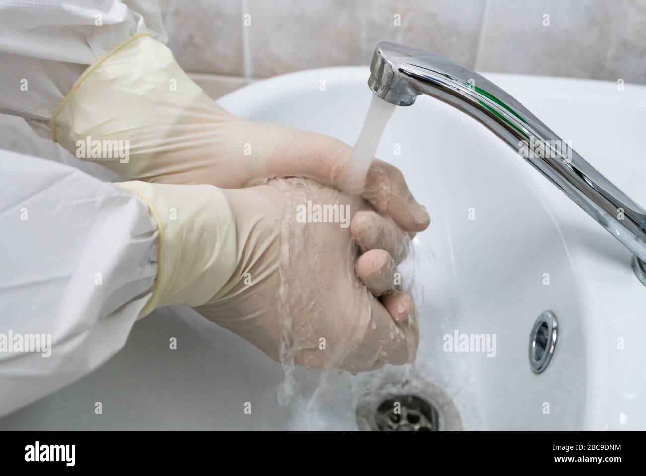 Il chirurgo lava e lavora le mani con guanti di gomma bianca. Disinfezione medica. Foto Stock