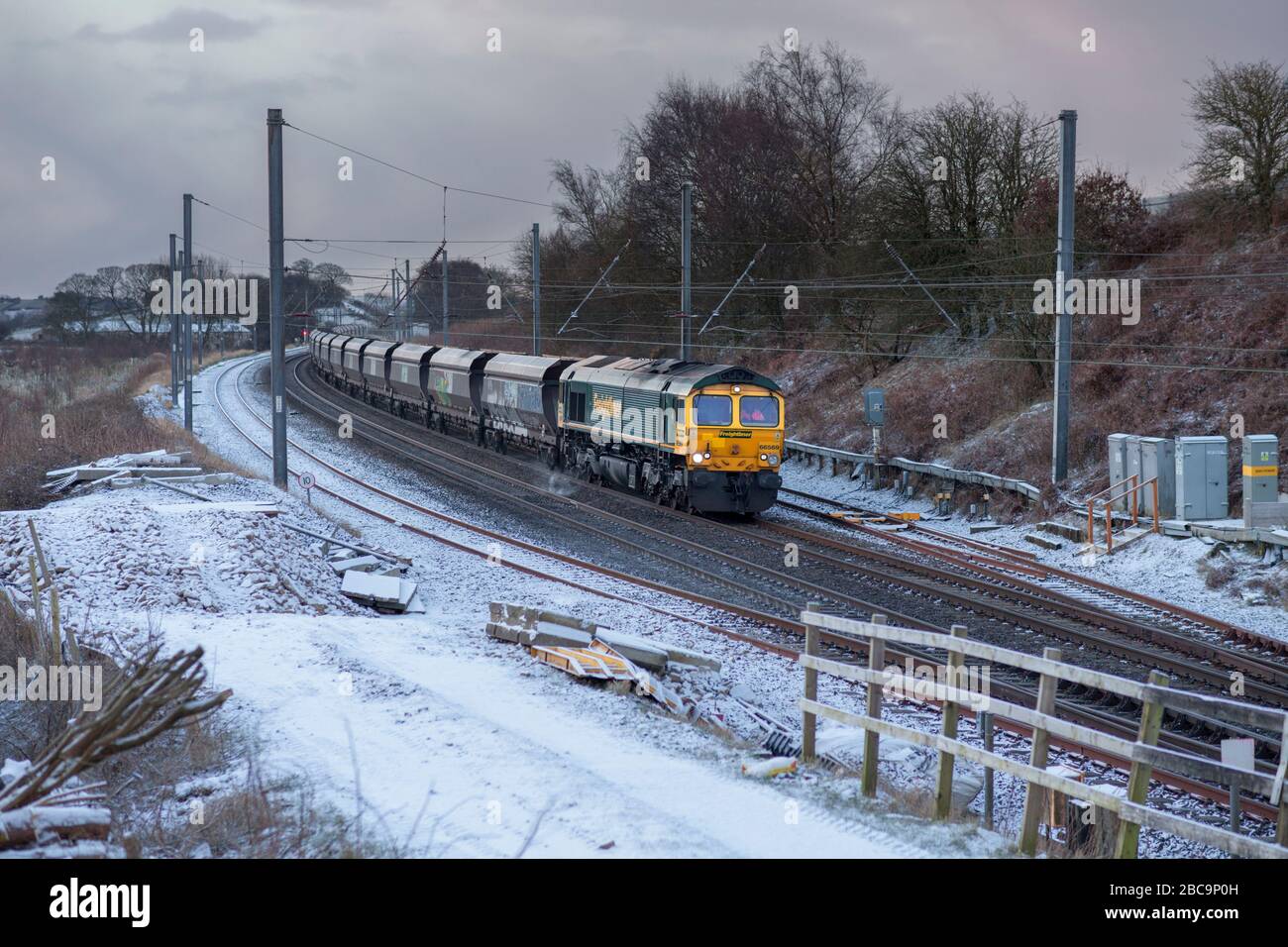 Freightliner classe 66 locomotiva 66569 trasporto di un treno di carbone vuoto sulla linea principale della costa occidentale nella neve Foto Stock