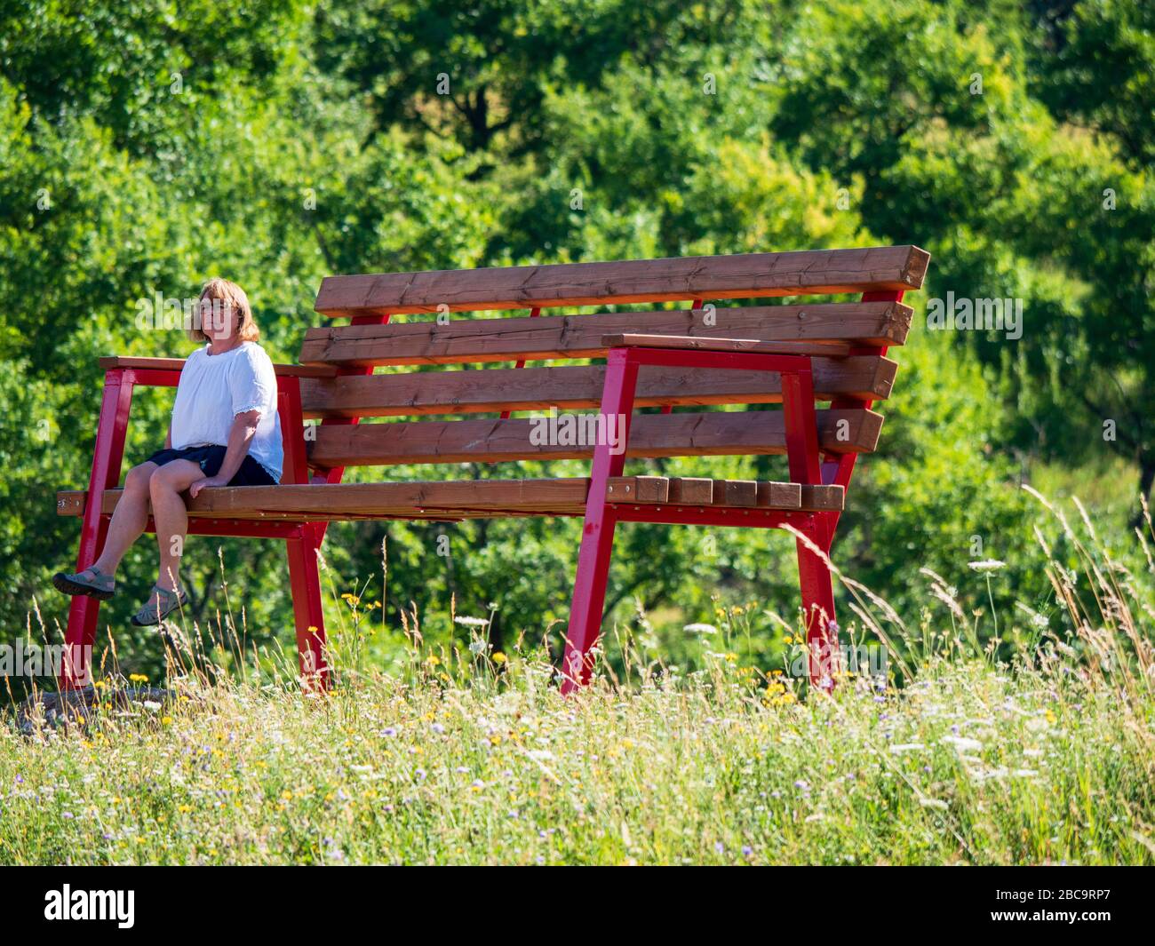 Donna siede su una grande banca enorme, Burgbernheim, Franconia medio, Franconia, Baviera, Germania Foto Stock