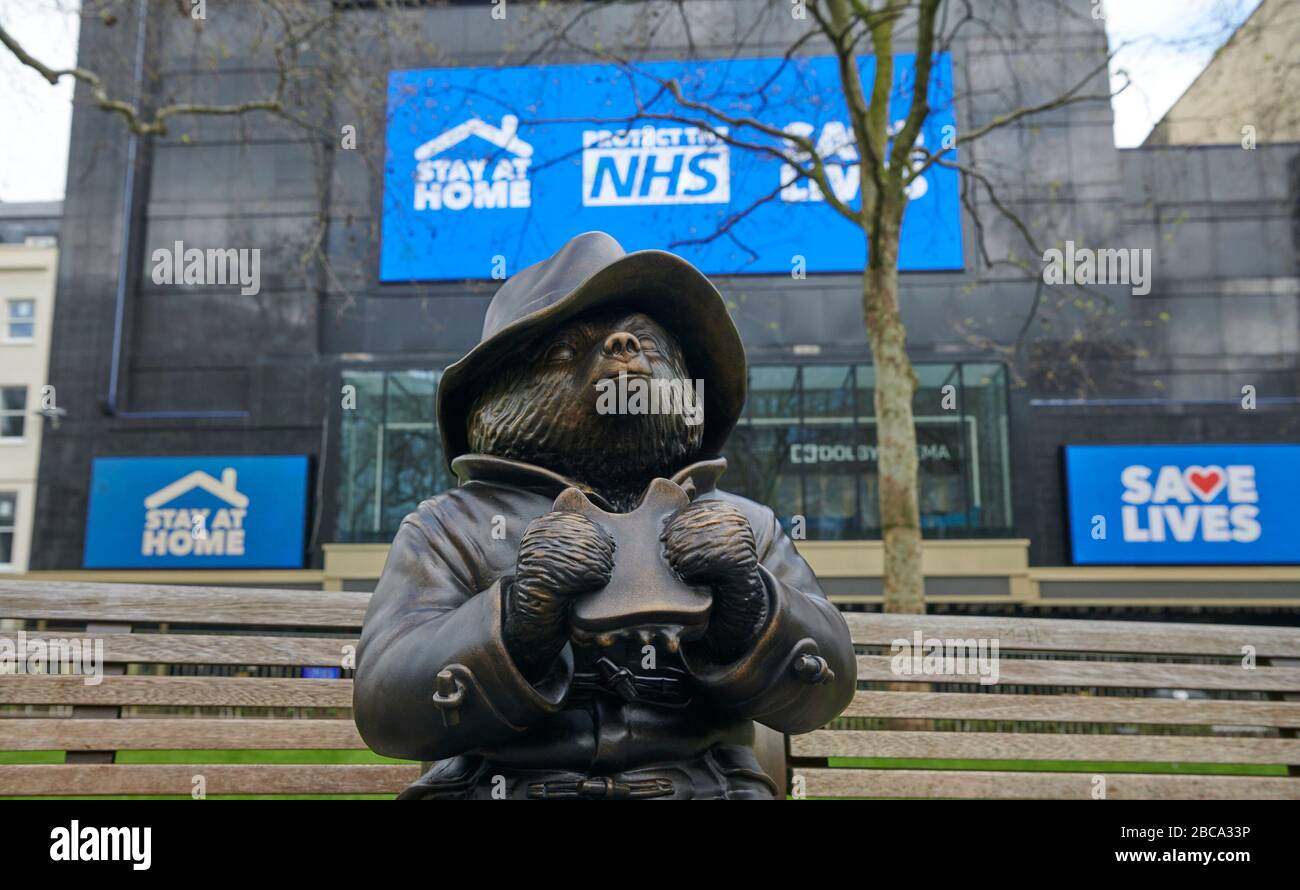 Londra. REGNO UNITO. 3rd aprile 2020. Una statua di bronzo dell'orso di Paddington si trova da sola su una panchina di Leicester Square, con messaggi per l'NHS sugli schermi del cinema Odeon durante il Global Pandemic Credit: Thomas Bowles/Alamy Live News Foto Stock