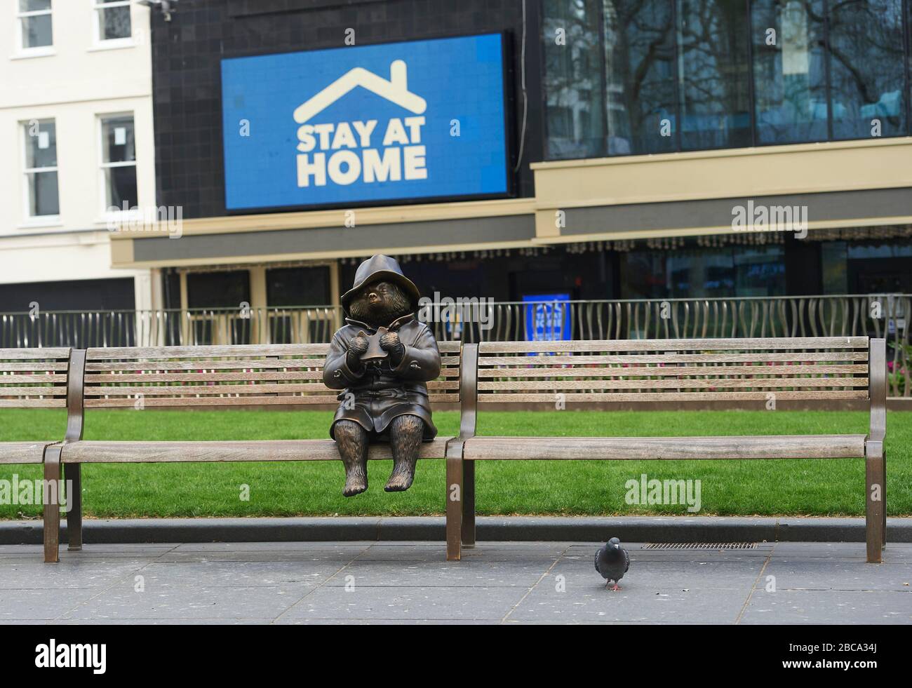 Londra. REGNO UNITO. 3rd aprile 2020. Una statua di bronzo dell'orso di Paddington si trova da sola su una panchina di Leicester Square, con messaggi per l'NHS sugli schermi del cinema Odeon durante il Global Pandemic Credit: Thomas Bowles/Alamy Live News Foto Stock