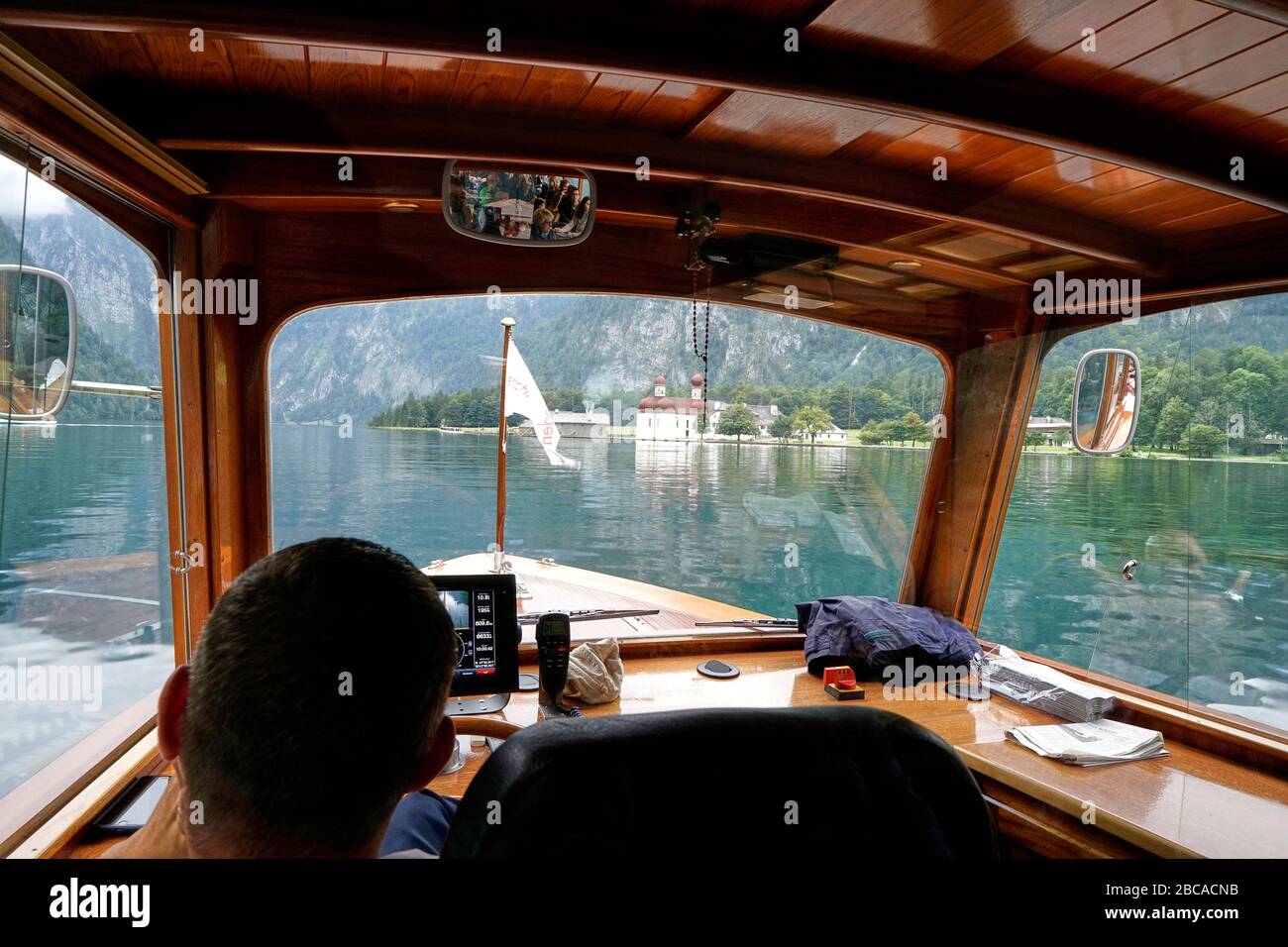 Germania, Baviera, alta Baviera, Berchtesgaden, Koenigsee, barca elettrica, dall'interno, posizione di guida, barca conducente, vista della cappella di San Bartolo Foto Stock