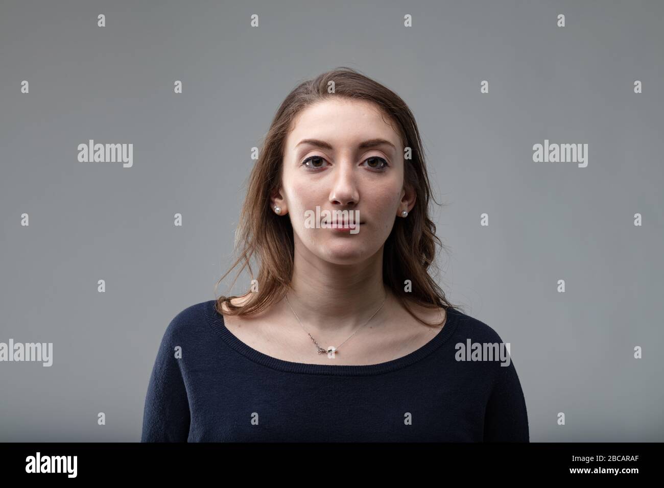 Donna di mezza età molto attraente, con capelli lunghi sulle spalle che indossano una parte superiore nera su uno sfondo grigio Foto Stock Donna di mezza età molto attraente, con capelli lunghi sulle spalle che indossano una parte superiore nera su uno sfondo grigio Foto Stock