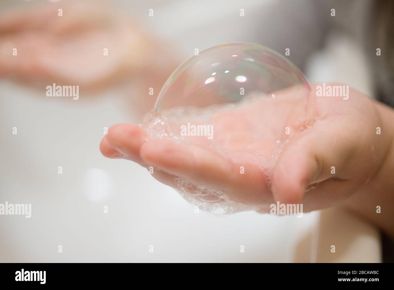 Primo piano di Young Boy Hand Holding Bubble sapone Foto Stock