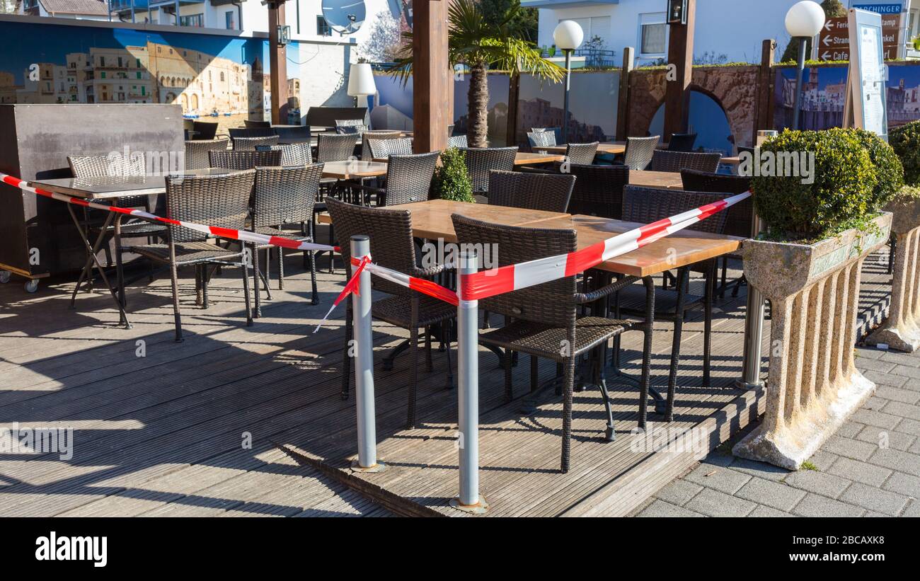 Patio di un ristorante con sedie e tavoli. Chiuso con nastro rosso - bianco. Chiuso a causa di restrizioni relative al Coronavirus (Covid-19). Foto Stock