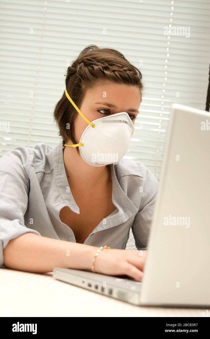 Primo piano di una maschera coronavirus indossata da una giovane donna che lavora in ufficio Foto Stock