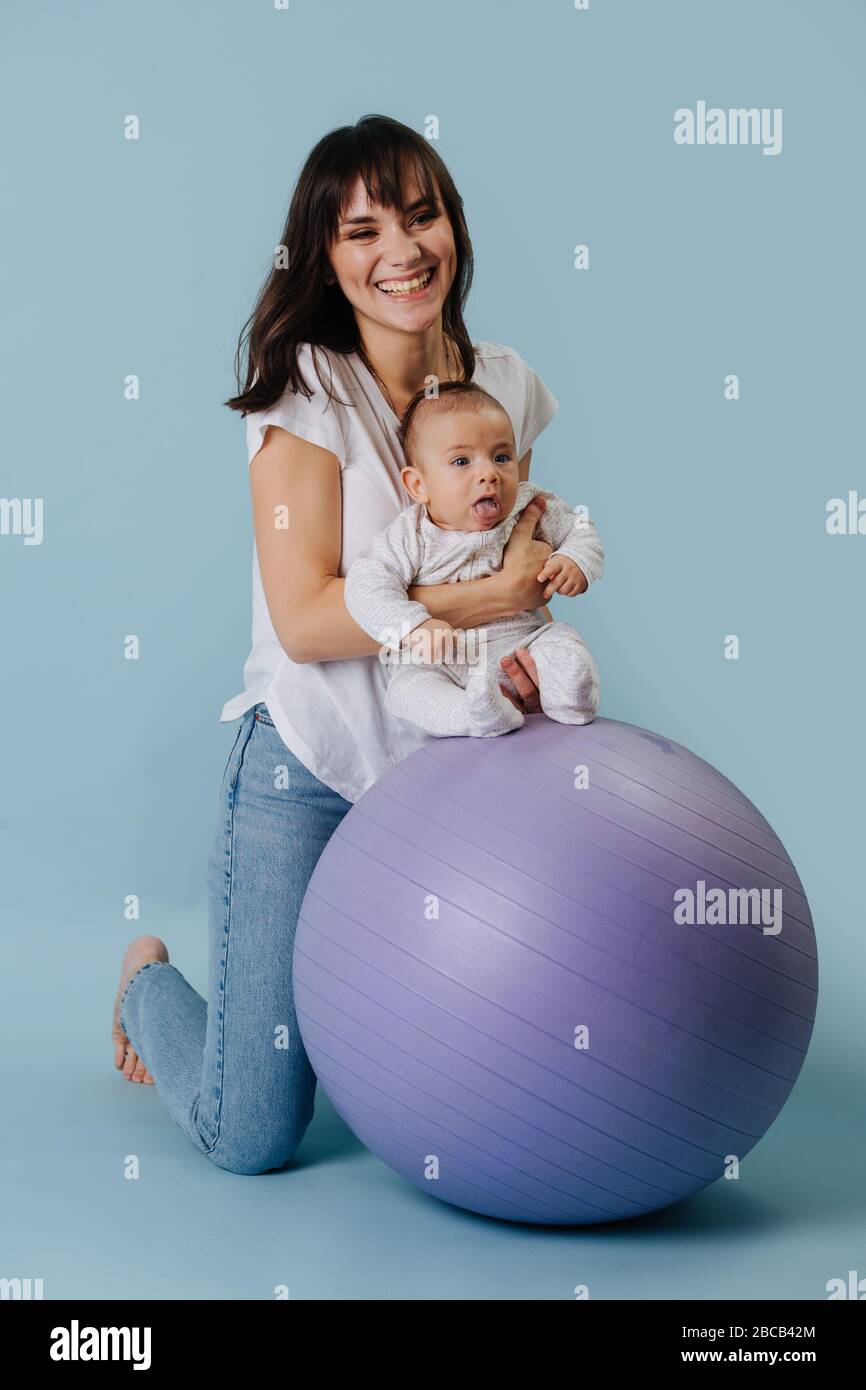 Bella mamma fa la carica con il bambino sulla sfera di idoneità Foto Stock