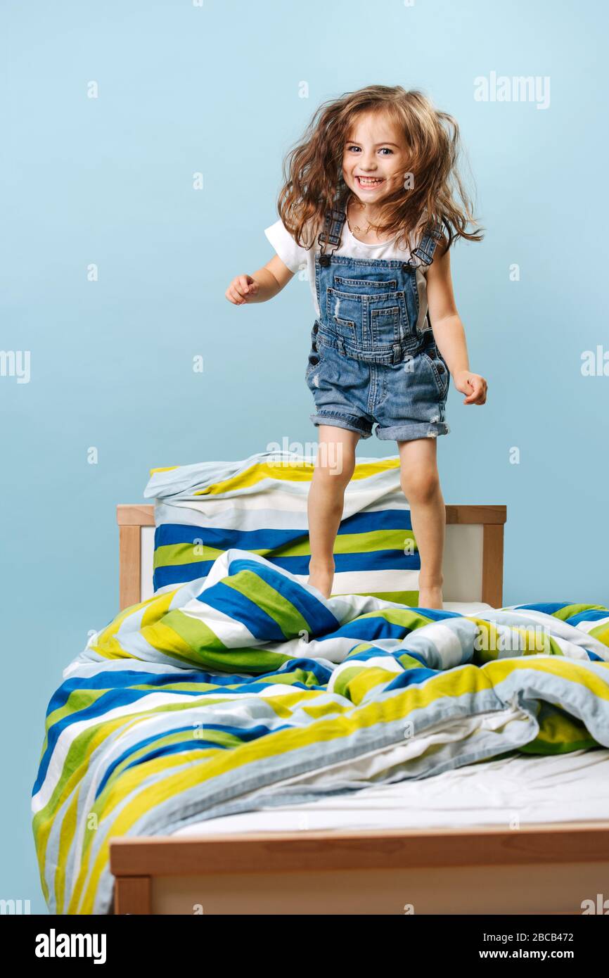 La ragazza ricciola salta sul letto prima di andare a letto Foto Stock