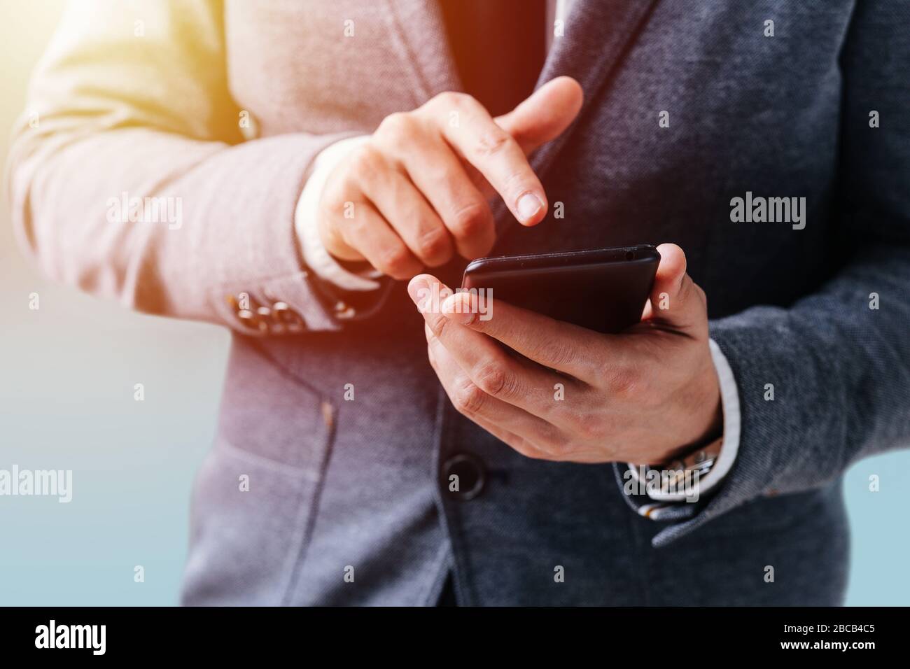 L'uomo d'affari tiene il telefono nelle sue mani e preme lo schermo Foto Stock