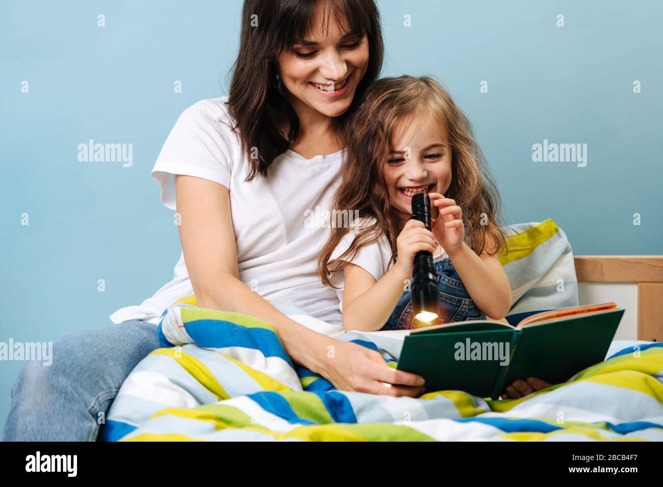 Giovane madre legge sua figlia un libro prima di andare a letto Foto Stock