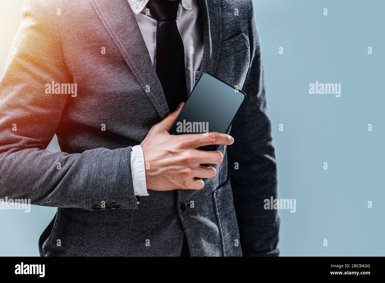 Un giovane uomo d'affari in giacca tiene un telefono Foto Stock