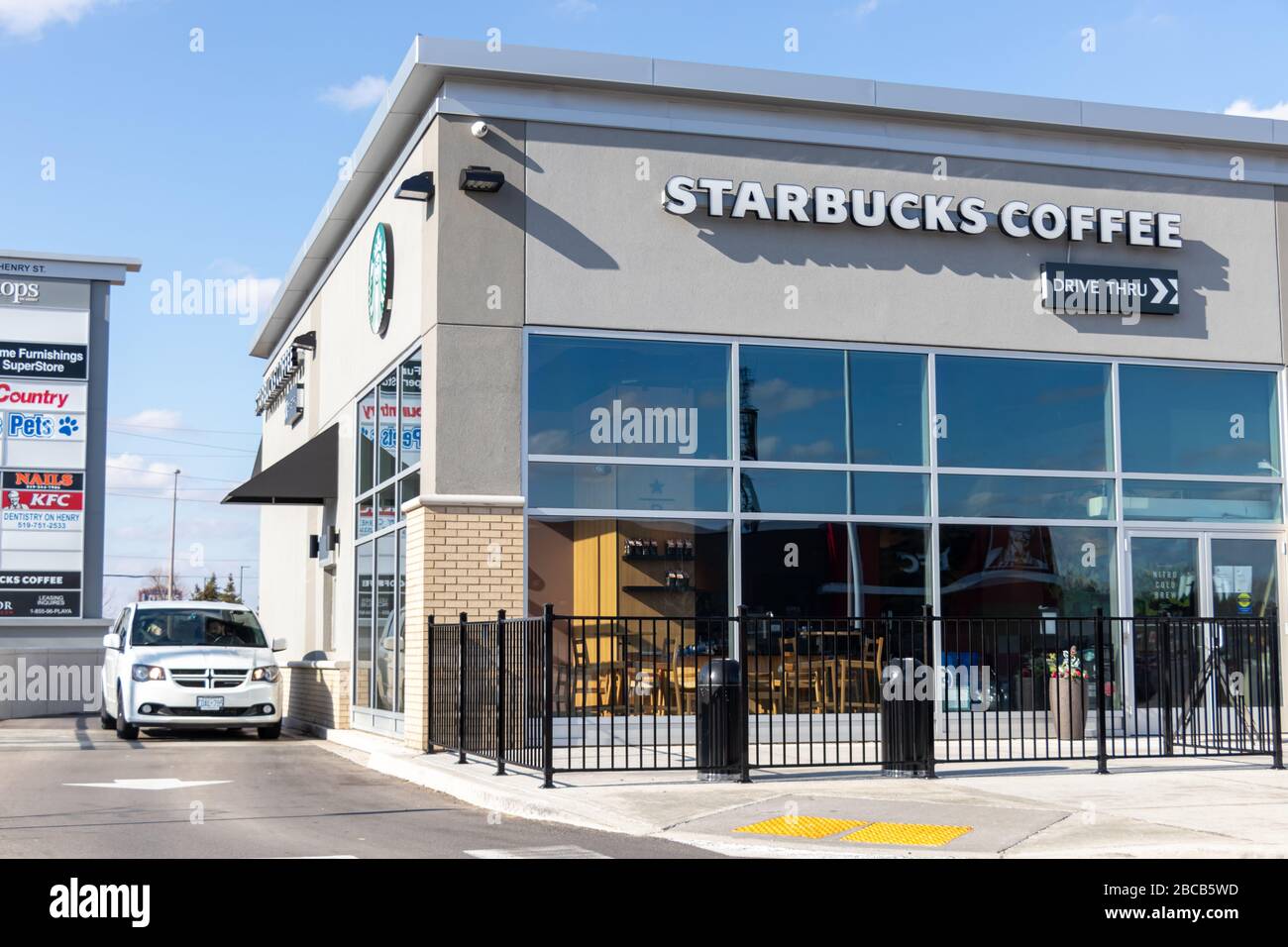 L'auto attende al finestrino drive-through come caffè Starbucks vuoto a causa della pandemia COVID-19, vista nella giornata di sole. Foto Stock
