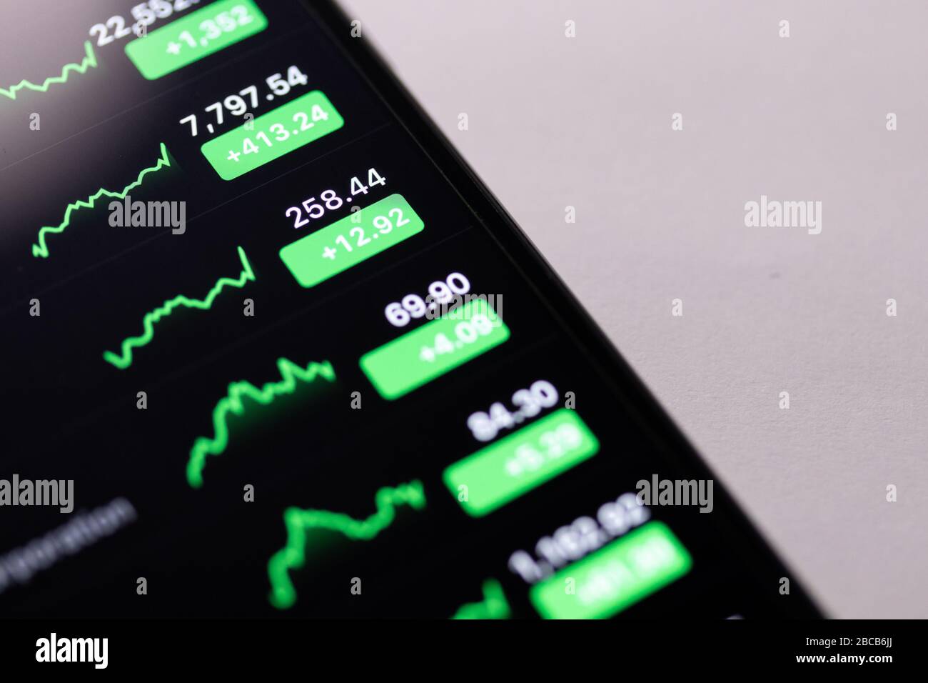 Elenchi, numeri e grafici dei mercati azionari verdi visualizzati sullo schermo di un telefono. Foto Stock