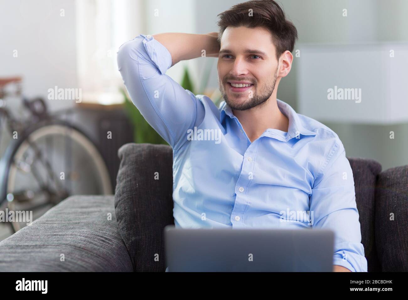 Uomo seduto sul divano con il computer portatile Foto Stock