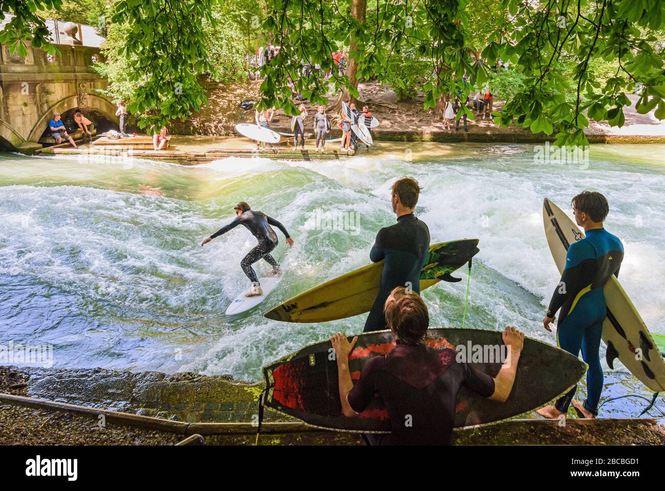 Surfers sul fiume Eisbachwelle, Giardino Inglese, Monaco, Baviera, Germania Foto Stock