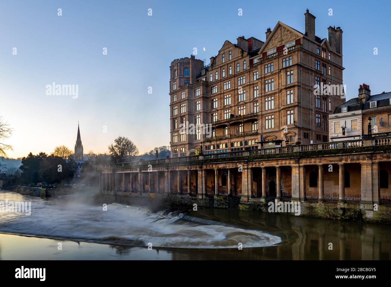 L'Empire Hotel vicino al Pulteney Bridge all'alba con il Colonnade sotto Newmarket Row e la Pulteney WEir sul fiume Avon, Bath, Inghilterra Regno Unito Foto Stock