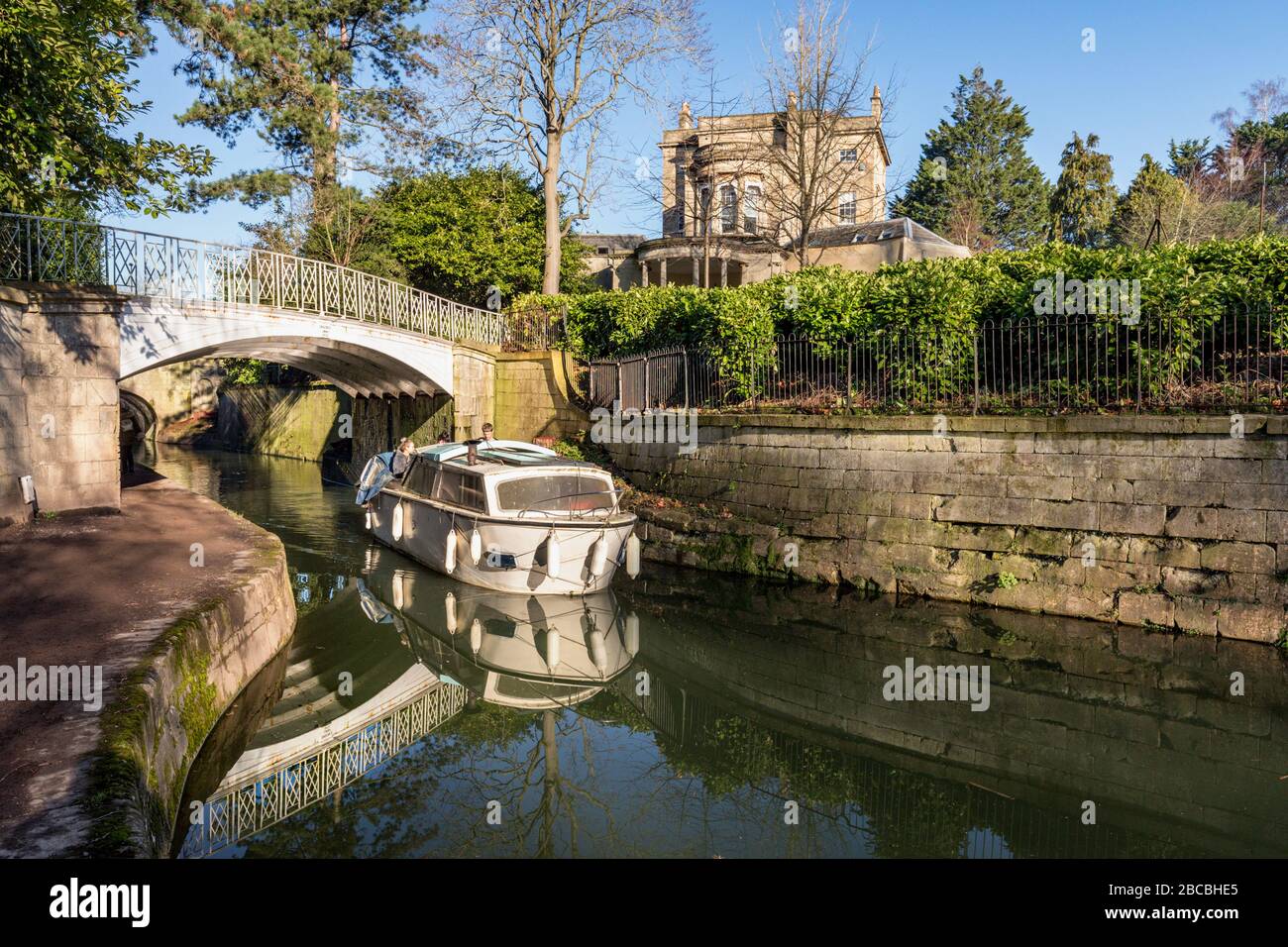 Una chiatta viaggia sotto un ponte di ferro sopra il Kennet e il canale Avon ai Sydney Gardens, Bath, Somerset England UK Foto Stock