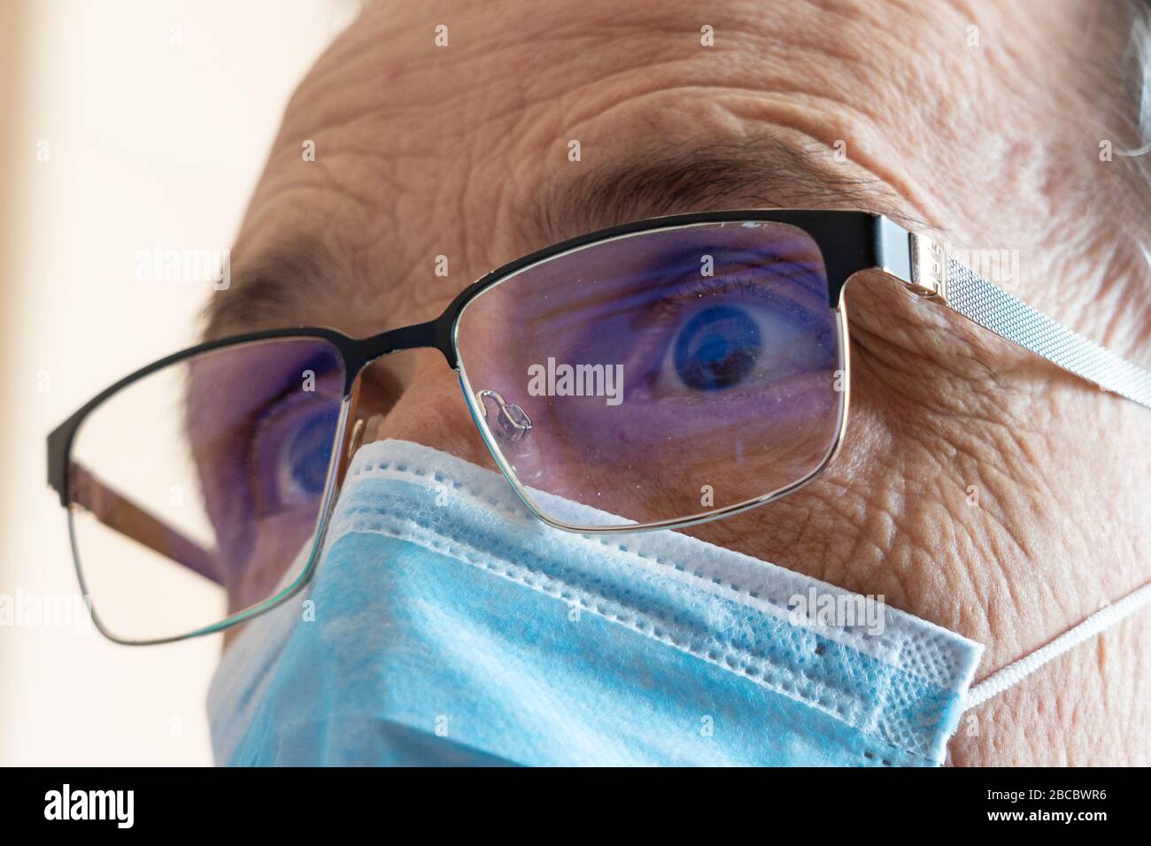 Visualizzare le notizie. Un uomo in occhiali e una maschera guarda lo schermo. Primo piano. Foto Stock