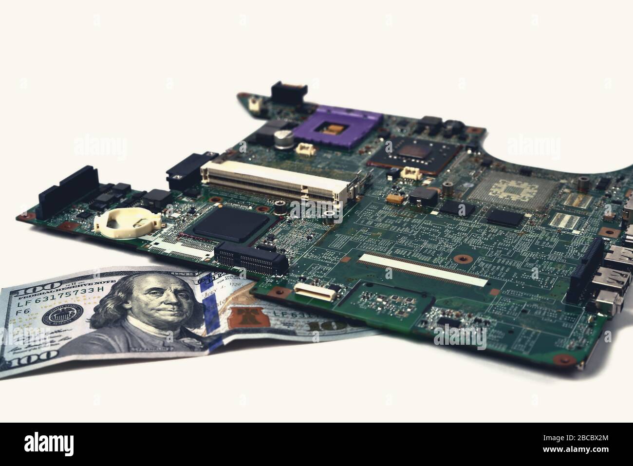 Un vecchio chip di un notebook si trova su una fattura di cento dollari, uno sfondo bianco, tonificante, un primo piano Foto Stock