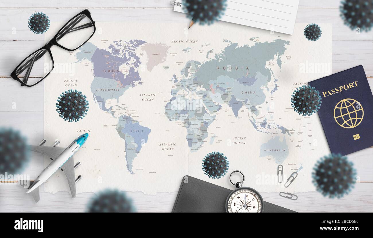 Il concetto di pericolo e incapacità di viaggiare causato dall'epidemia di coronavirus. Mappa del mondo, passaporto, occhiali, aereo, bussola circondata da corona Foto Stock