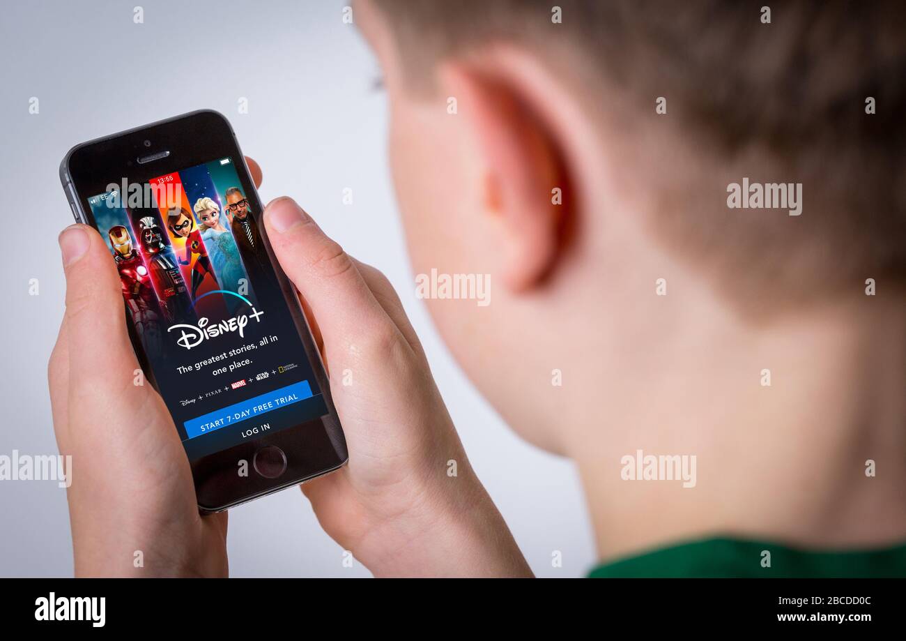 Un adolescente che utilizza l'app Disney Plus su un telefono cellulare Foto Stock