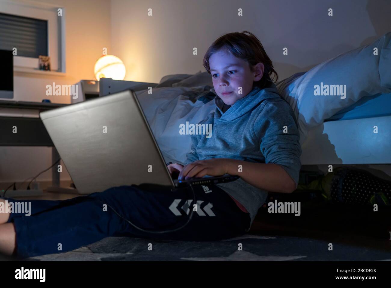 Ragazzo, a casa sul computer, laptop, nella stanza dei bambini, giocando un gioco, Foto Stock
