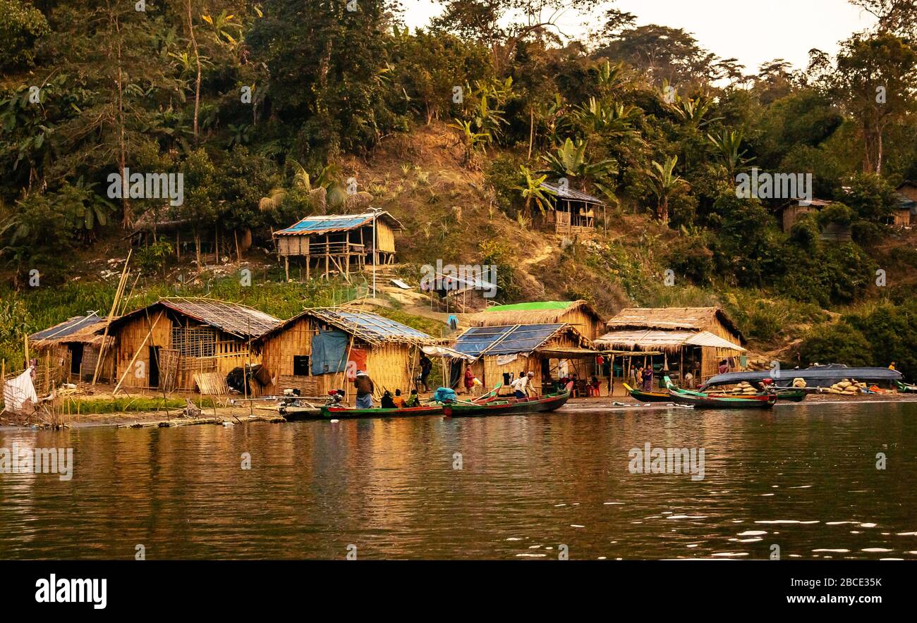 Una parte di una comunità di villaggio che vive accanto al fiume Sangu in case fatte di Bamboo. La gente usa le barche per andare in viaggio le loro esigenze quotidiane. Foto Stock