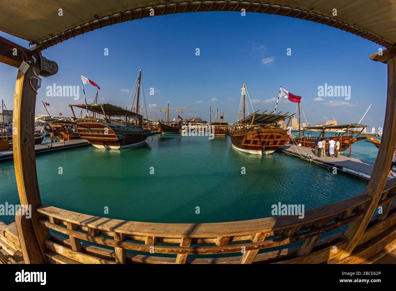 Tradizionali barche in legno (dhows) a Katara spiaggia Qatar vista luce del giorno con bandiera Qatar e nuvole nel cielo Foto Stock