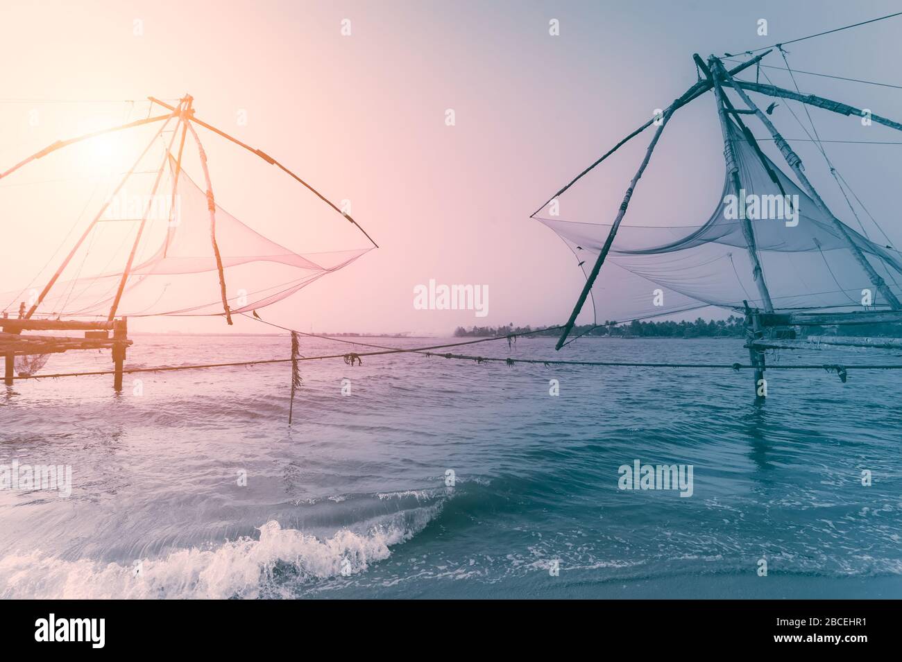 Tramonto sulla spiaggia tropicale. Paesaggio della costa dell'oceano con la silhouette cinese delle reti da pesca a Cochin (Kochi). India meridionale, Kerala, Kochin Foto Stock