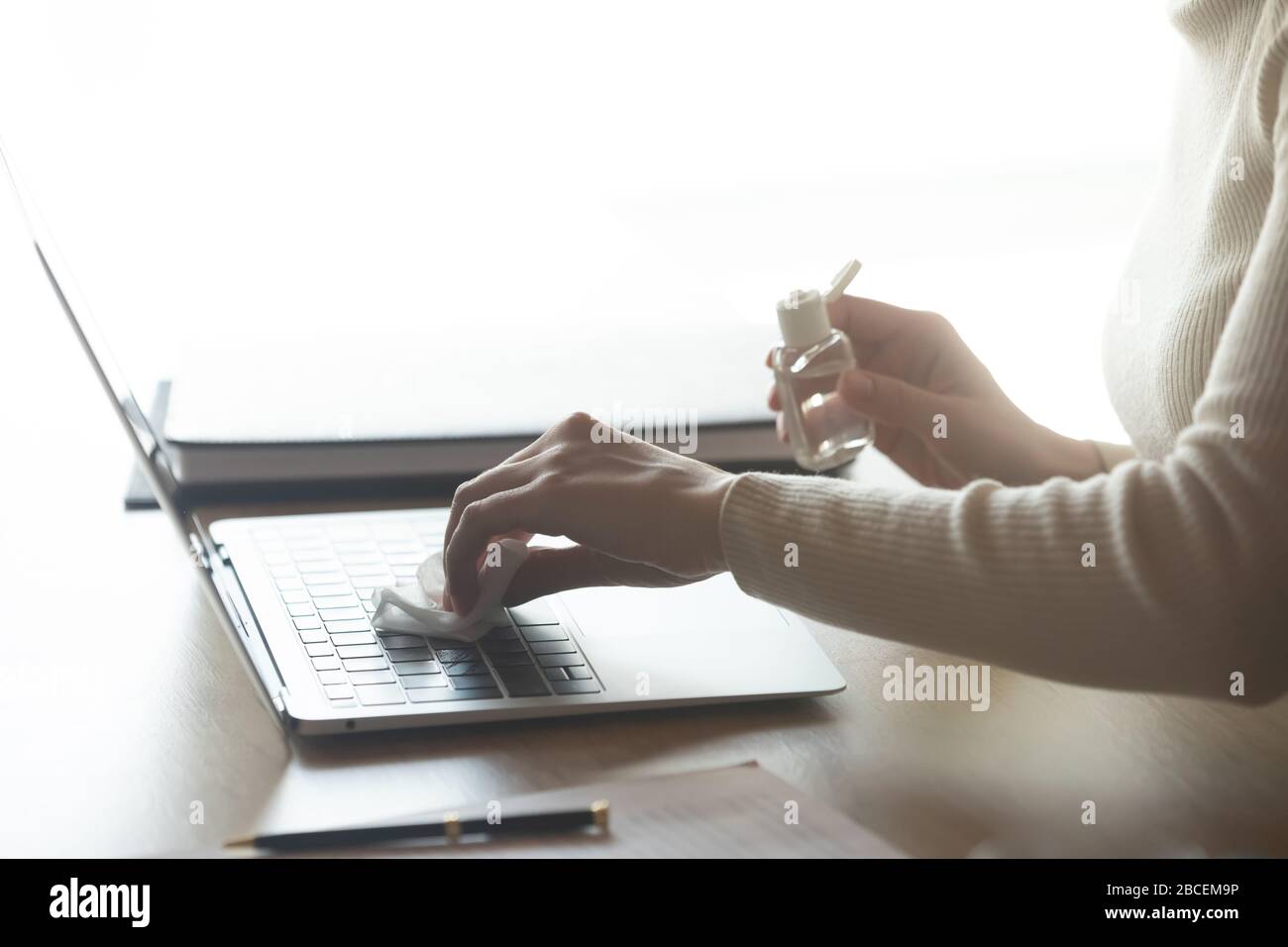 Giovane donna pulizia tastiera portatile con gel antisettico su tovagliolo. Foto Stock