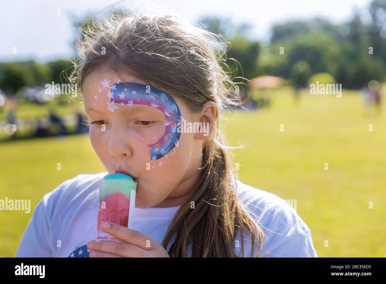 Teenager con la vernice del viso che mangia il gelato di colore della ciotola della pioggia. Foto Stock