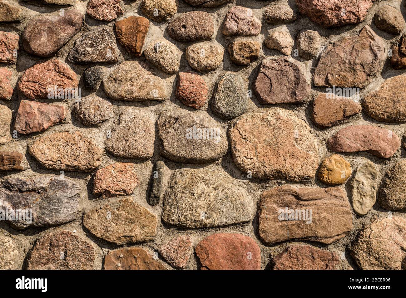 Pietre fissate con mortaio di cemento. Un muro di pietre di ciottoli. Foto Stock