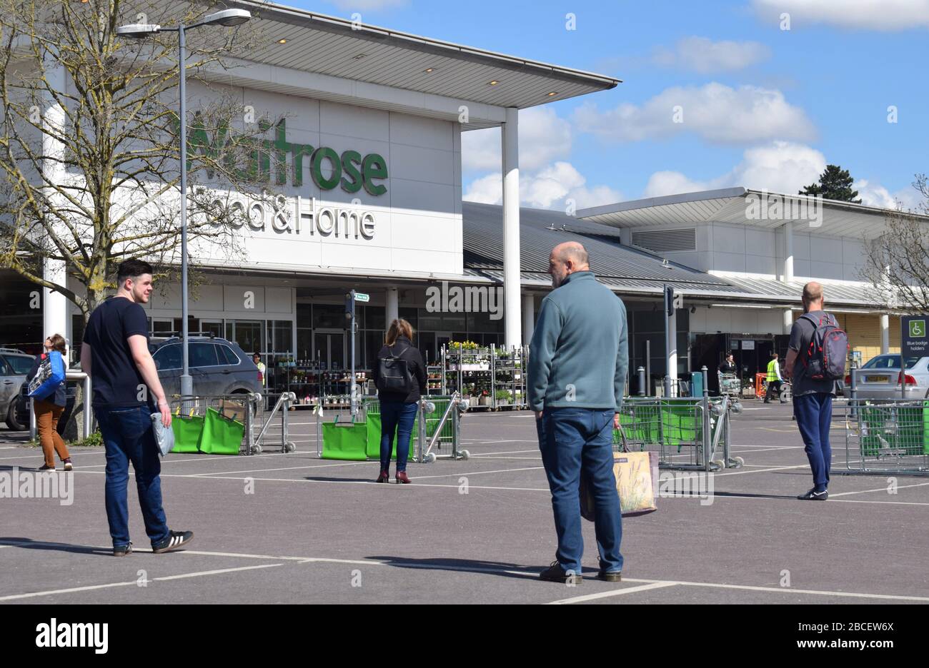 Le persone che si accodano a 2 metri di distanza in un parcheggio mentre aspettano di entrare in un supermercato per acquistare generi alimentari nel Regno Unito durante la pandemia Coronavirus Covid19 Foto Stock