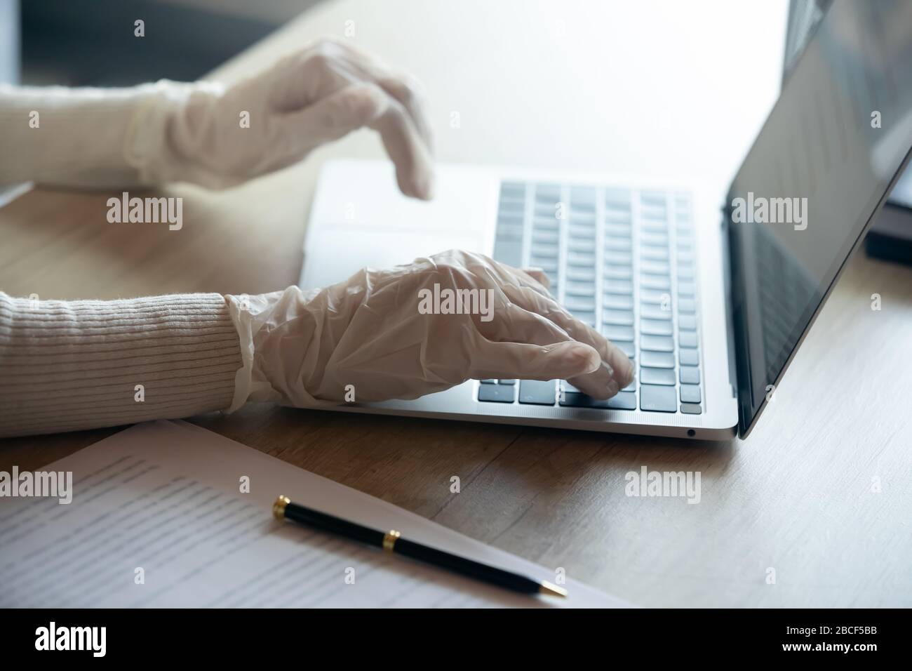 Giovane donna d'affari prudente che lavora sul computer con guanti. Foto Stock