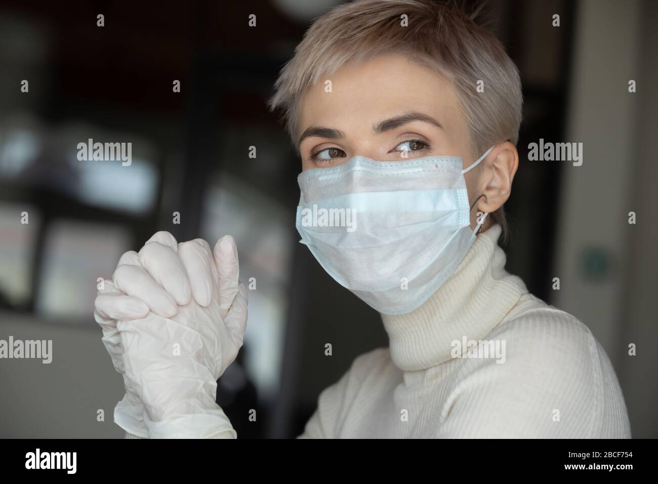 Donna attenta agli anni '30 che indossa una maschera medica e guanti protettivi. Foto Stock