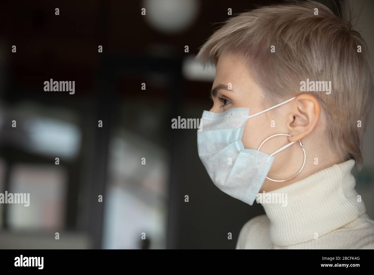 Giovane donna con taglio corto con maschera facciale di protezione del respiro. Foto Stock