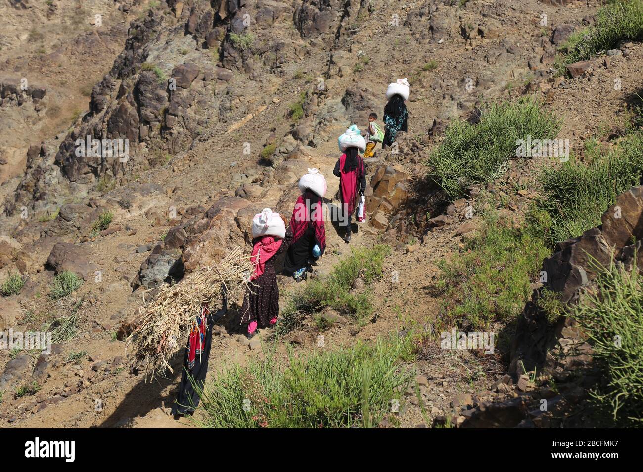 Taiz / Yemen - 02 Apr 2017: I bambini yemeniti portano cibo e bevande sulle strade di montagna accidentate a causa dell'assedio e della guerra alla città di Taiz Foto Stock