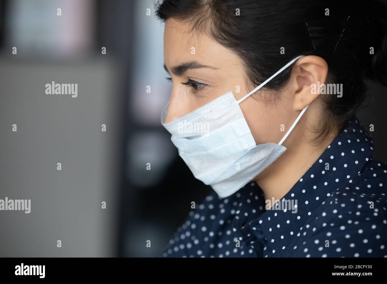 Vista laterale millenario etnia indiana businesswoman in maschera medica facciale. Foto Stock