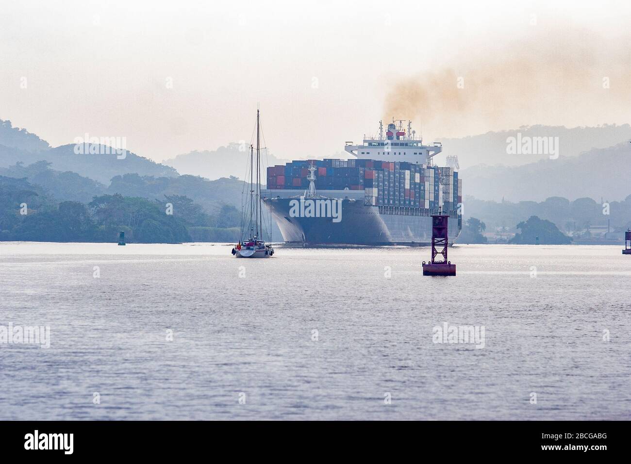 La nave container incontra uno yacht a vela nel lago Gatun, sezione del canale di Panama Foto Stock