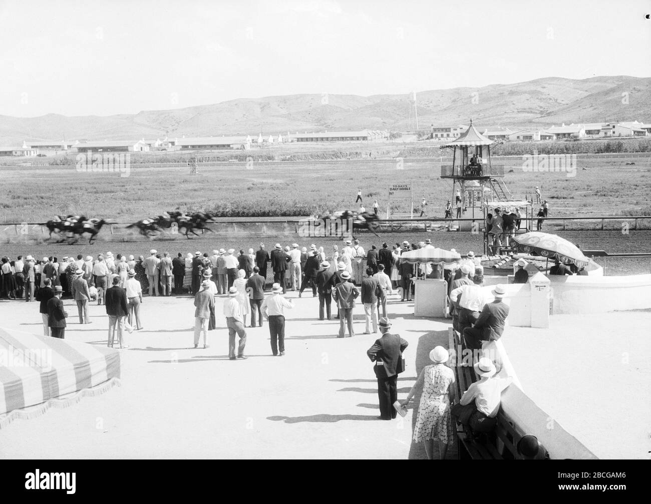 Gli spettatori guardano una corsa di cavalli dalla ringhiera all'Ippodromo di Agua Caliente, Tijuana, Messico, alla fine degli anni '20. Fotografia di Burton Holmes. Foto Stock