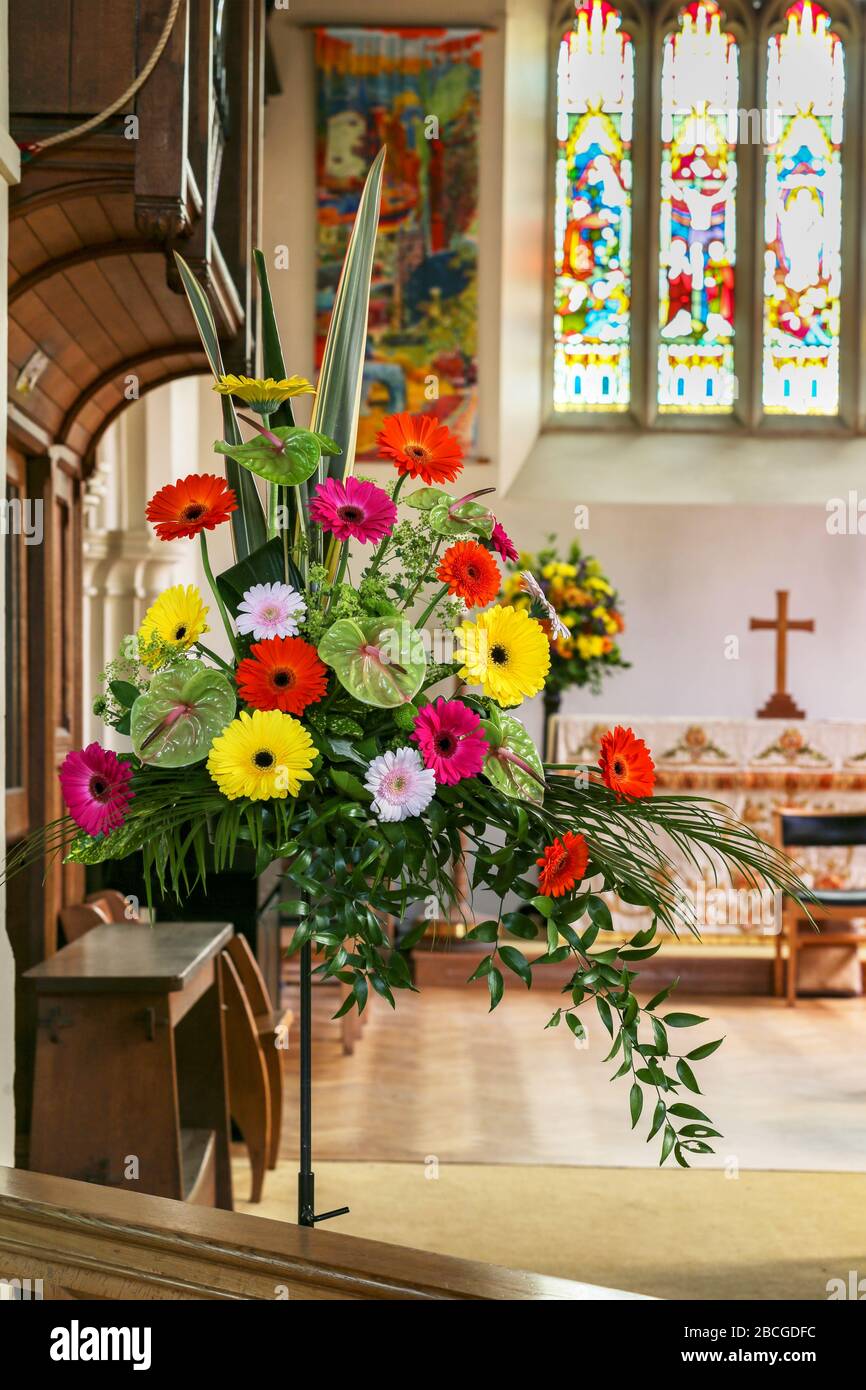 Un vivace, colorato, matrimonio, fiori arrangiamento vicino l'alter in una chiesa inglese, chiesa d'Inghilterra, Foto Stock