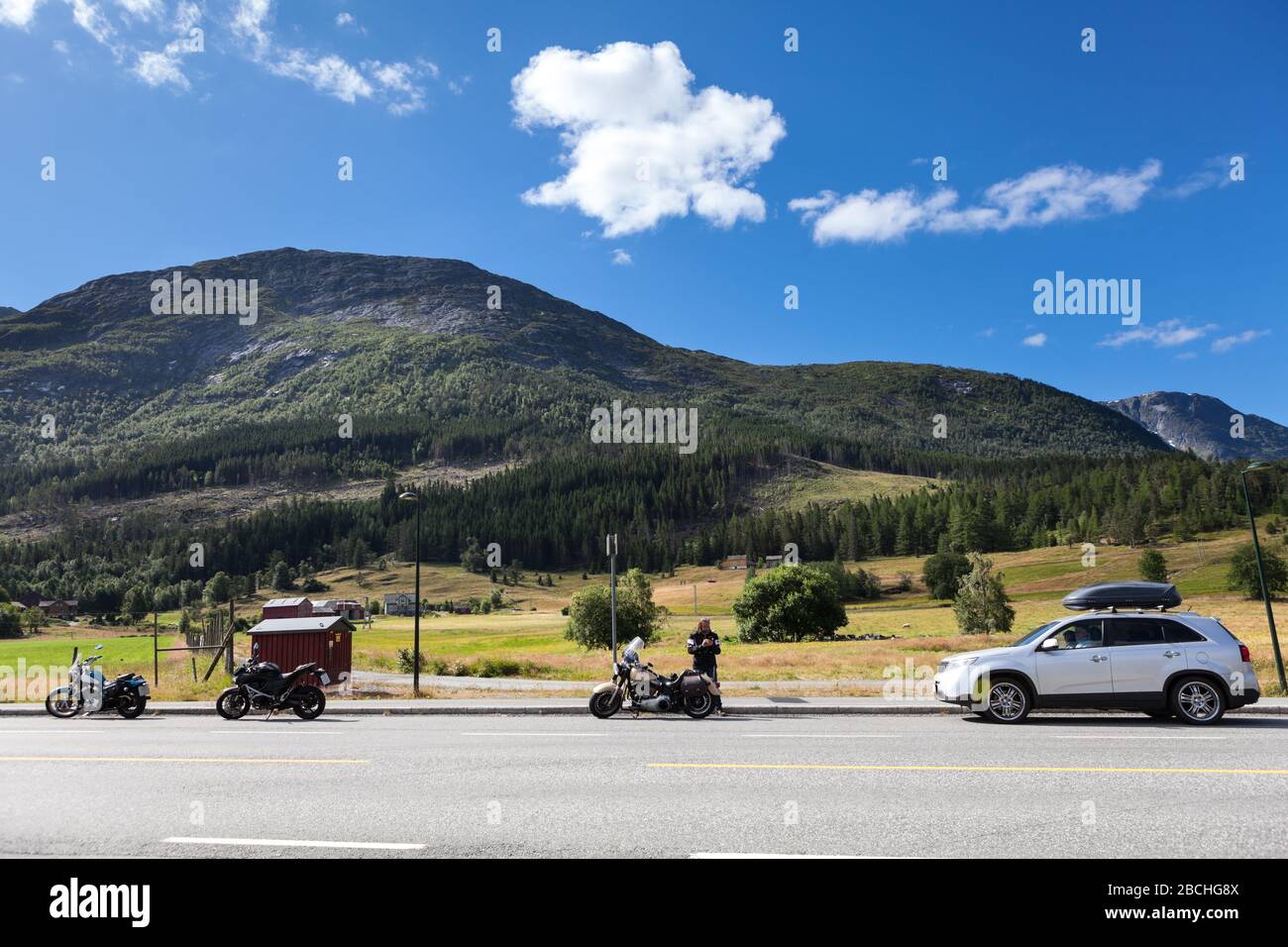 Tre moto e auto in piedi sulla strada di autostrada in montagna della Norvegia. Viaggi in Scandinavia in auto. Europa Foto Stock