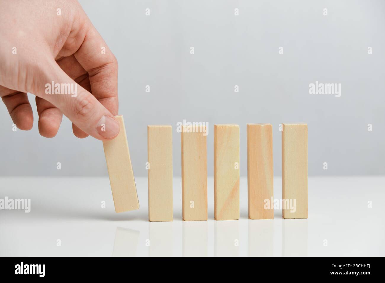 Il concetto di creazione di un business in fasi. La mano tiene blocchi di legno su uno sfondo bianco. Primo piano. Foto Stock