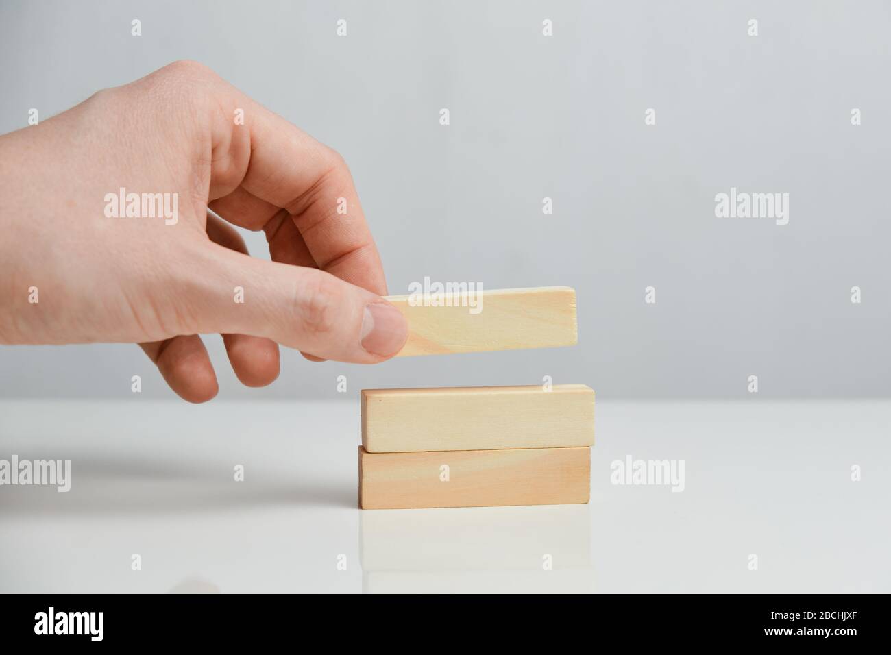 Il concetto di pianificazione graduale. La mano tiene blocchi di legno su uno sfondo bianco. Primo piano. Foto Stock