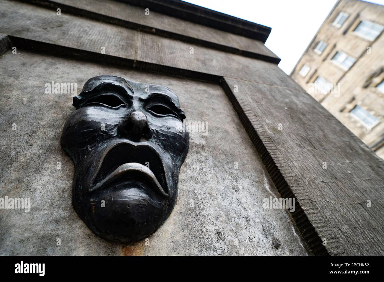 Maschera teatrale in bronzo rilievo con triste volto su High Street wellhead sul Royal Mile a Edimburgo, Scozia, Regno Unito, per indicare la tristezza della cancellazione del festival Edinburgh Fringe 2020. Foto Stock