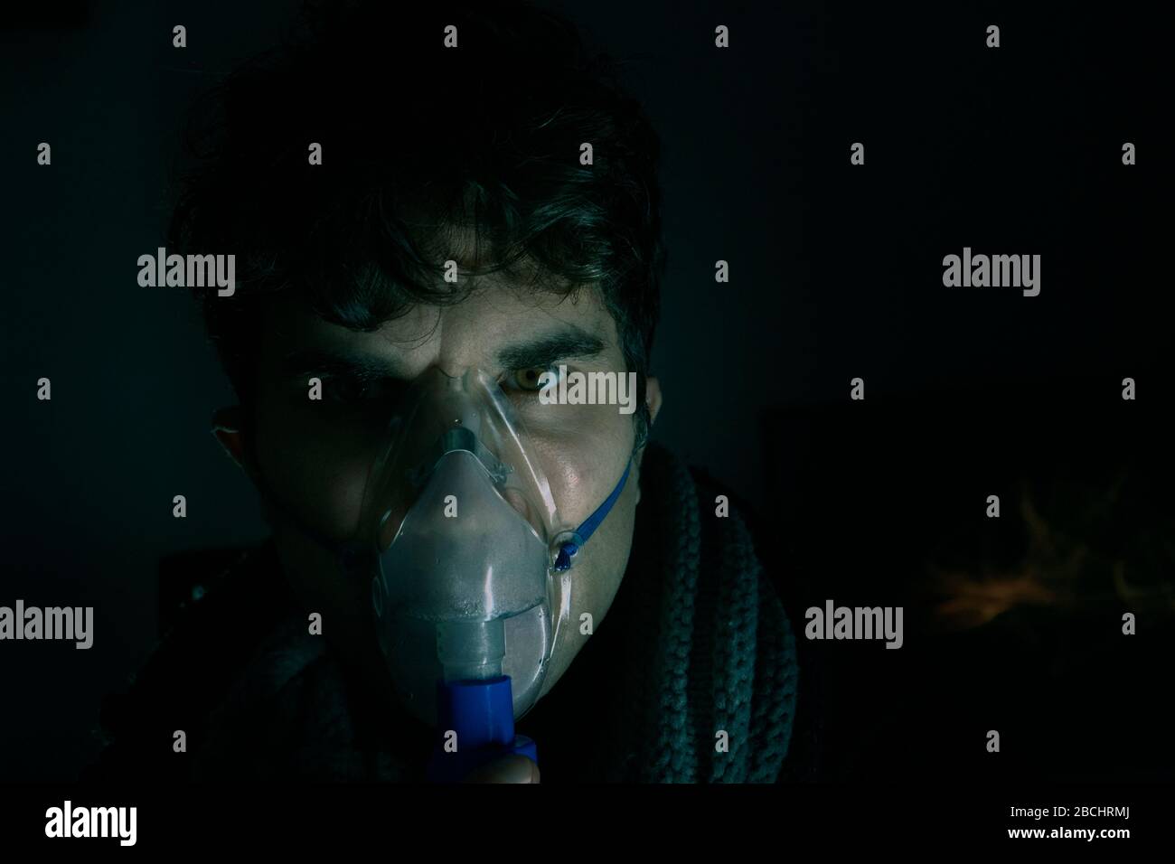 Dark Portrait of man Using Steam Vapor Inhaler nebulizzatore fare aerosol inalazione medicina trattamento a casa o ospedale influenza e asma bronchite vir Foto Stock