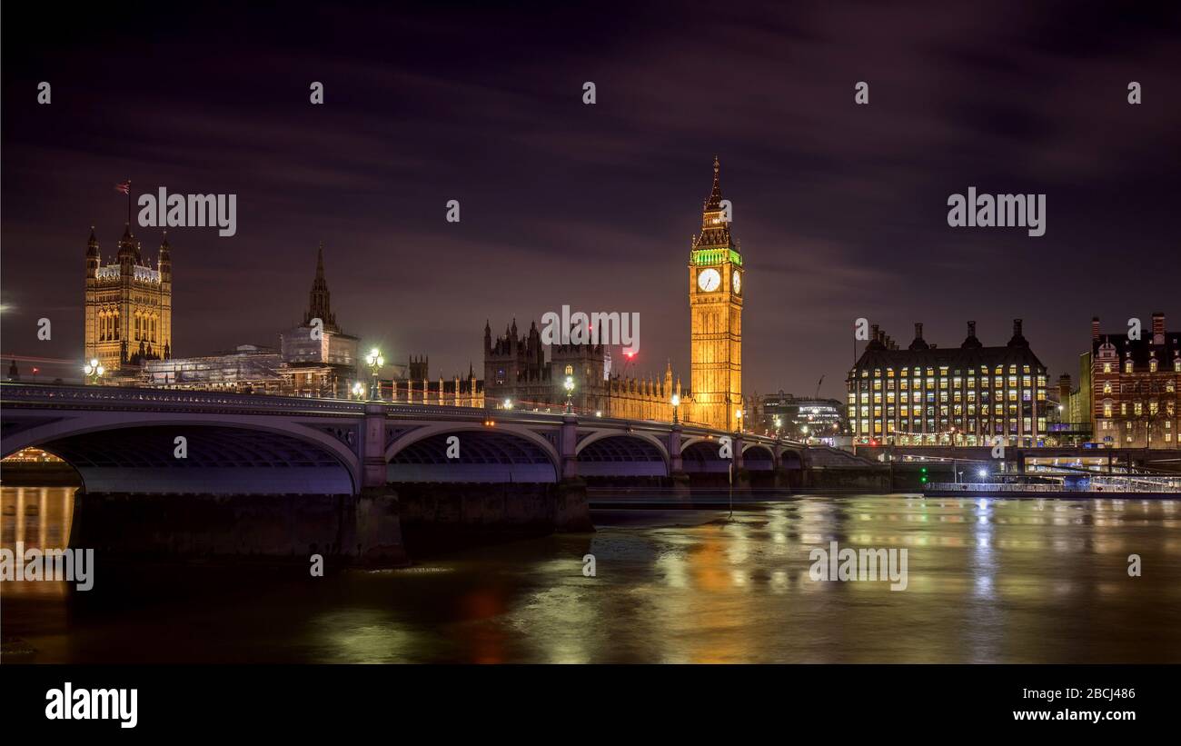 Guardando attraverso il Tamigi a Londra con il Westminster Bridge e le Houses of Parliament e il Big ben illuminati di notte. Foto Stock