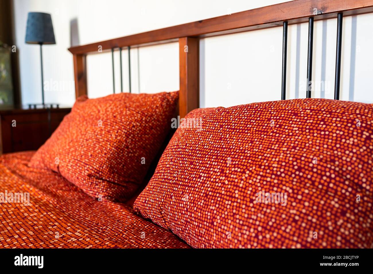 Camera da letto vintage retro con letto rosso arancio cuscino in camera con testiera in legno in casa in Europa Foto Stock