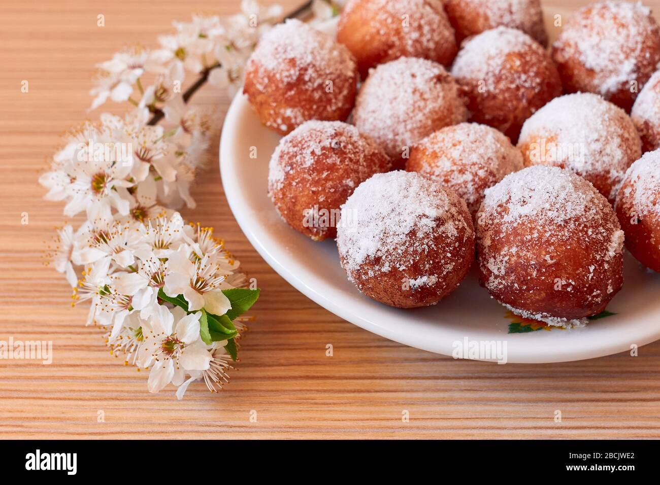 Buchi di ciambella fatti in casa con un brach fiorente sulla scrivania, durante l'isolamento pandemico Foto Stock